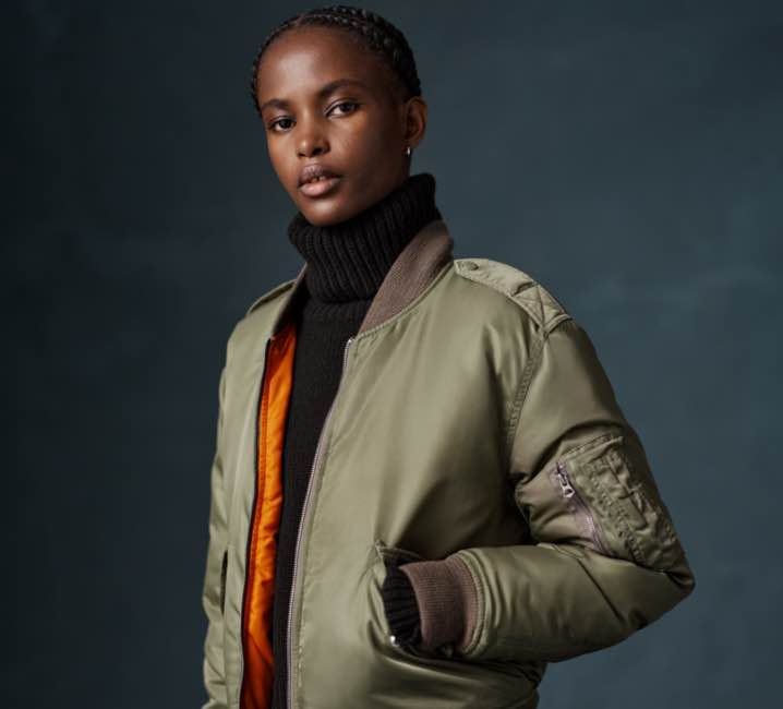 Woman wears green down-filled bomber jacket.