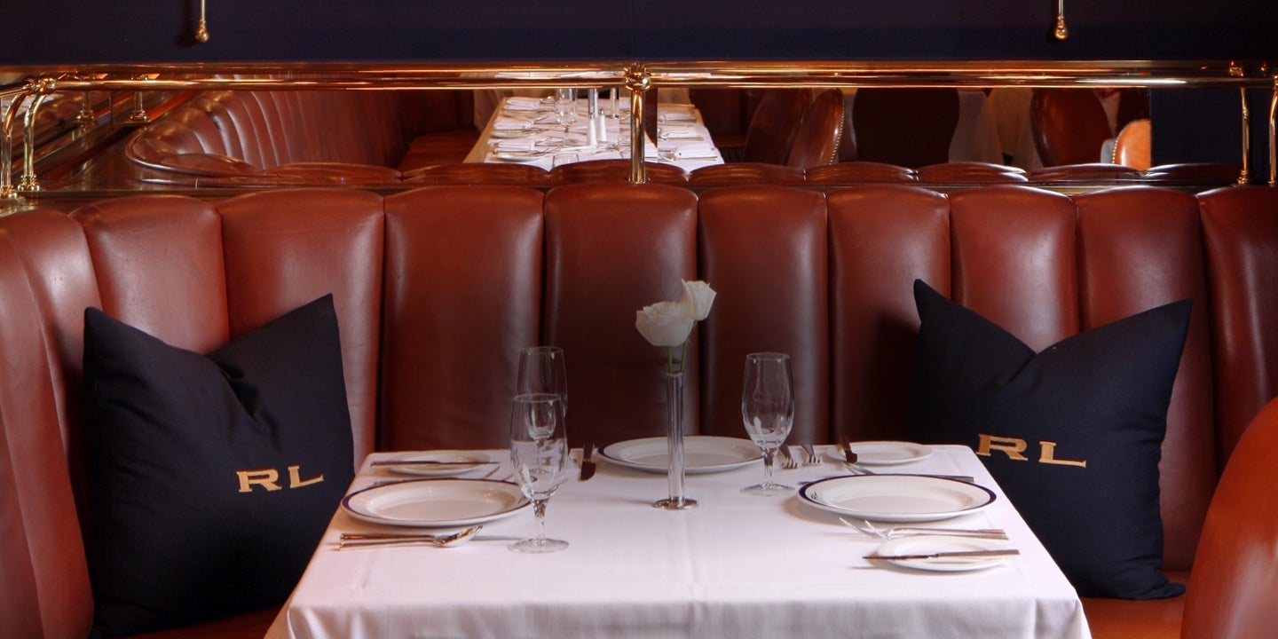 Tufted brown leather booth with navy RL pillows.
