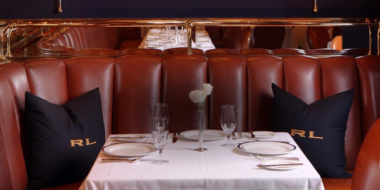 Tufted brown leather booth with navy RL pillows.