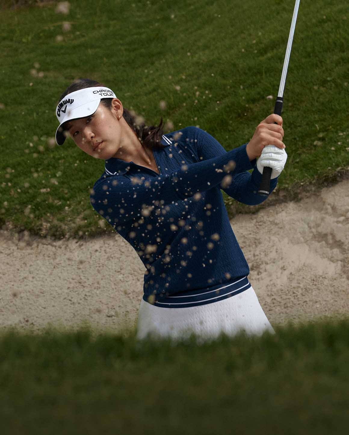 Andrea Lee on golf course wears light green Polo and pleated skirt.