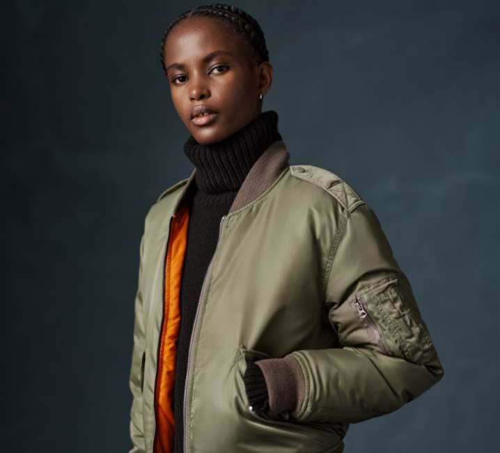 Woman wears green down-filled bomber jacket.