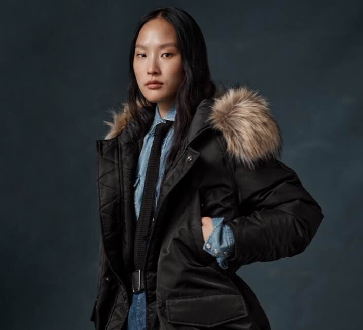 Woman wears black parka with faux-fur-trimmed hood.