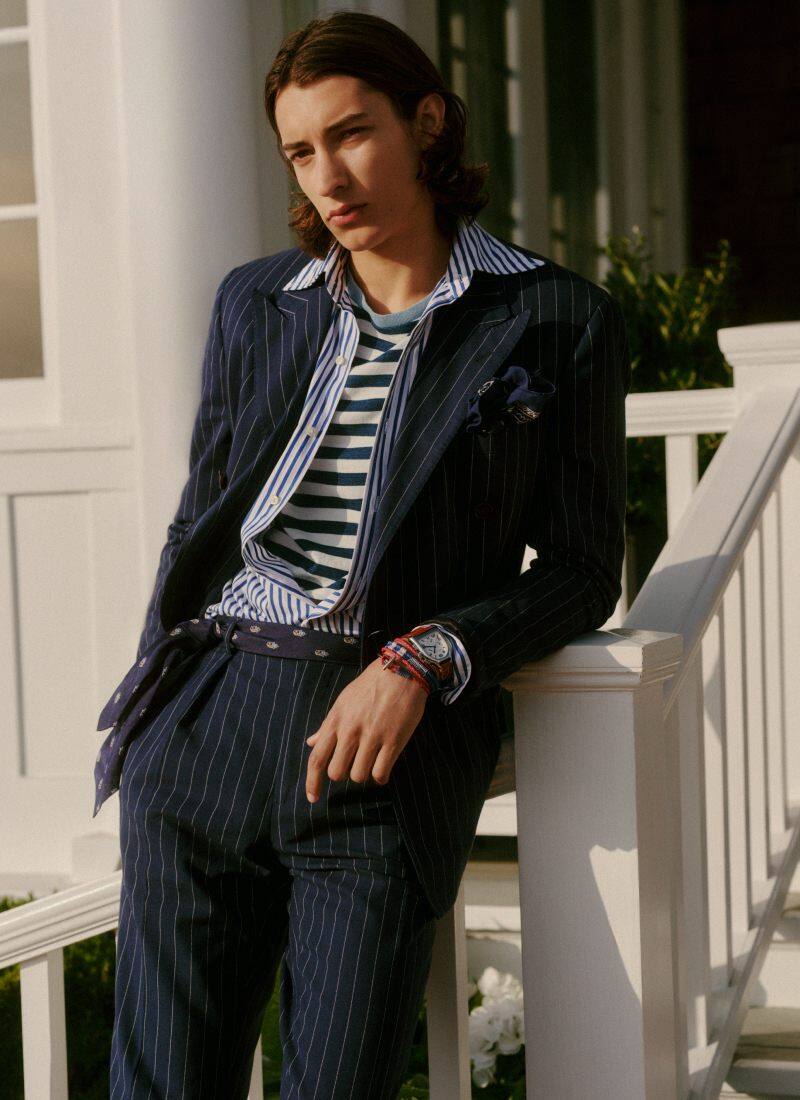 Man wears navy pinstripe suit over striped button-down and T-shirt.